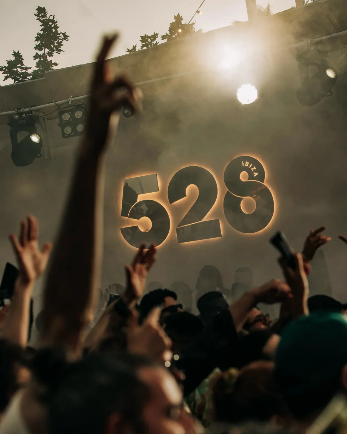 The glowing 528 Ibiza logo illuminates a foggy, energetic crowd at a nightclub with raised hands.