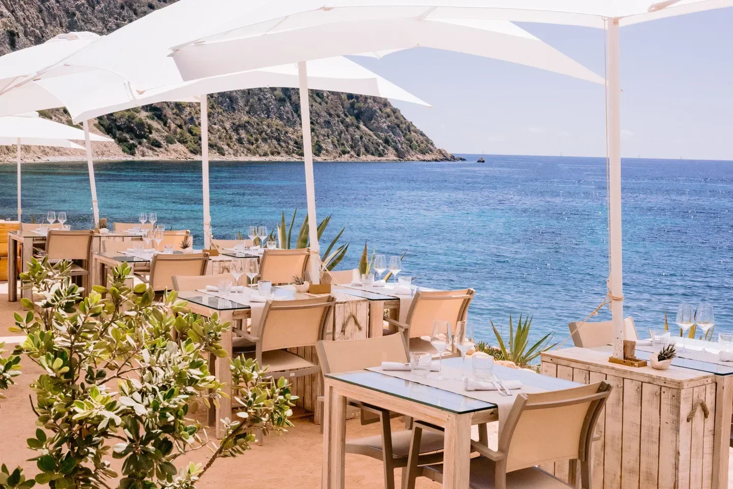 Seaside dining at Amante Ibiza, with tables set by the turquoise Mediterranean sea.