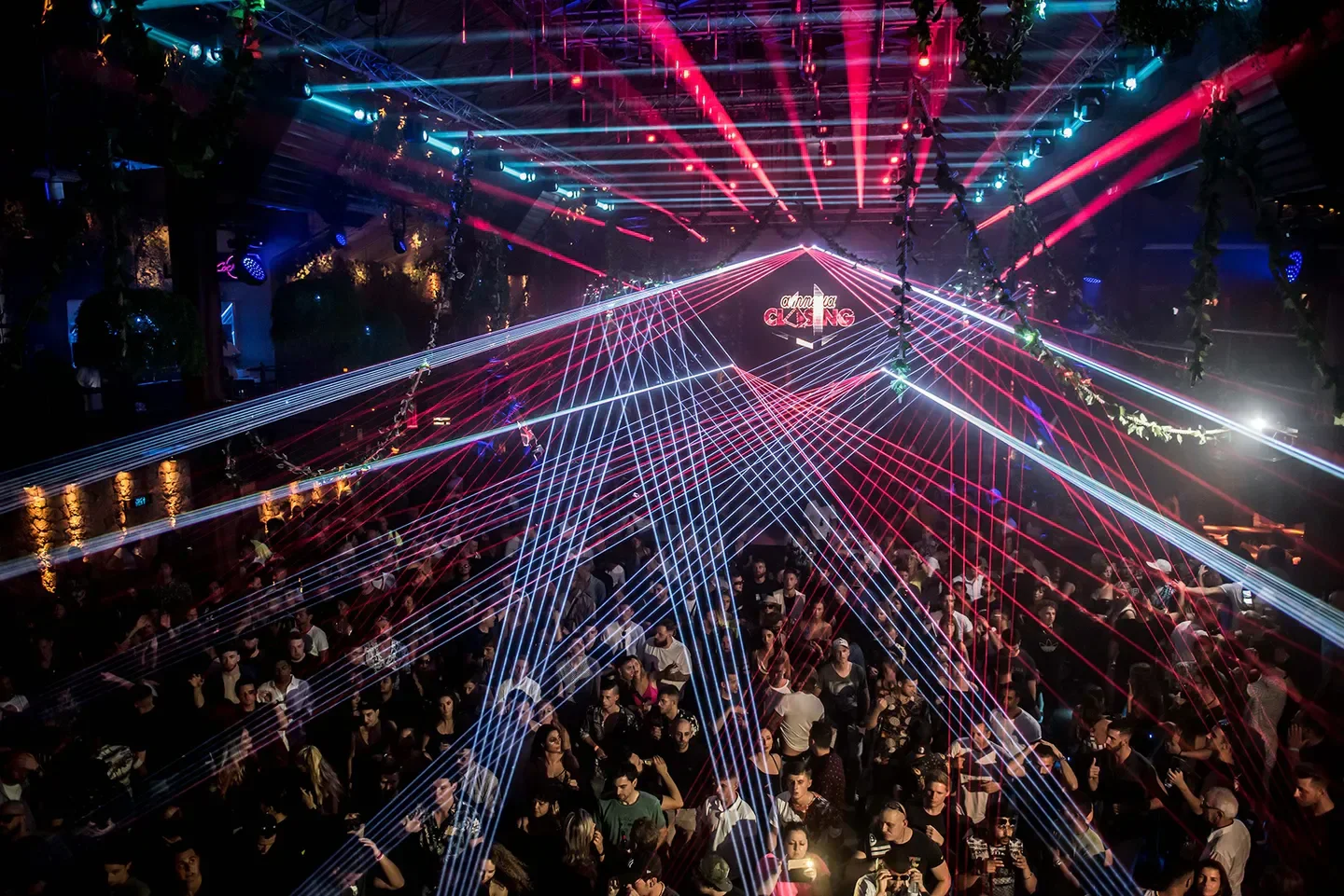High-energy crowd at Amnesia Ibiza nightclub, with vibrant laser light show and party atmosphere.