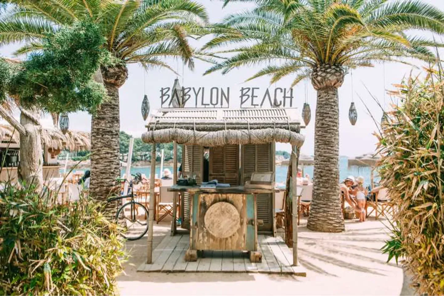 Babylon Beach Bar in Ibiza: Palm trees frame the rustic bar with beach views.
