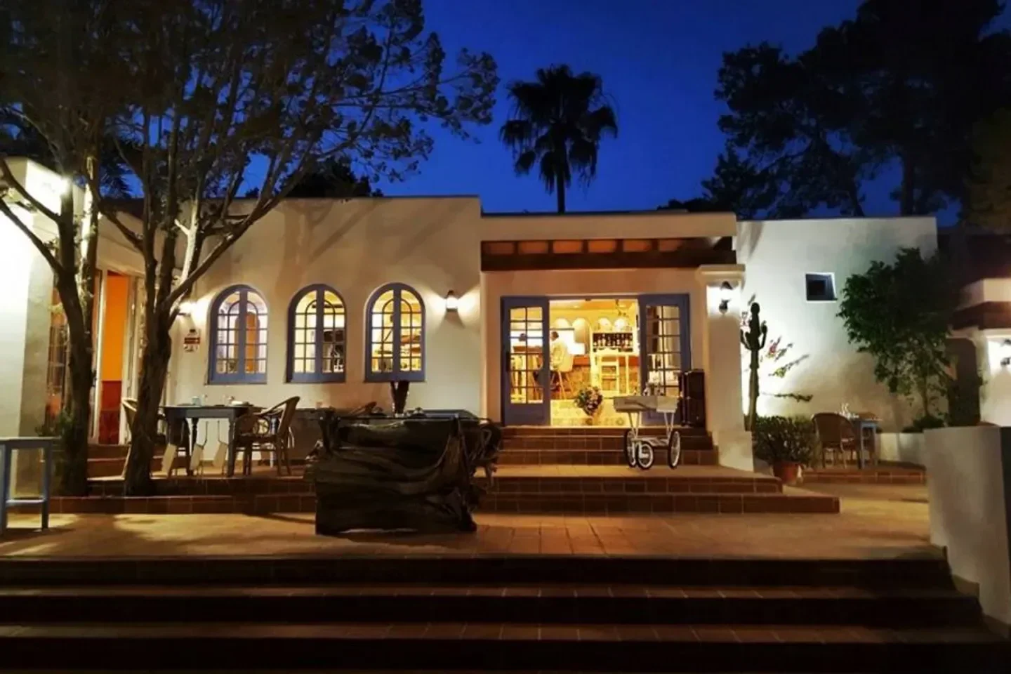 Exterior of Es Tragón restaurant in Ibiza at night, inviting and lit up.