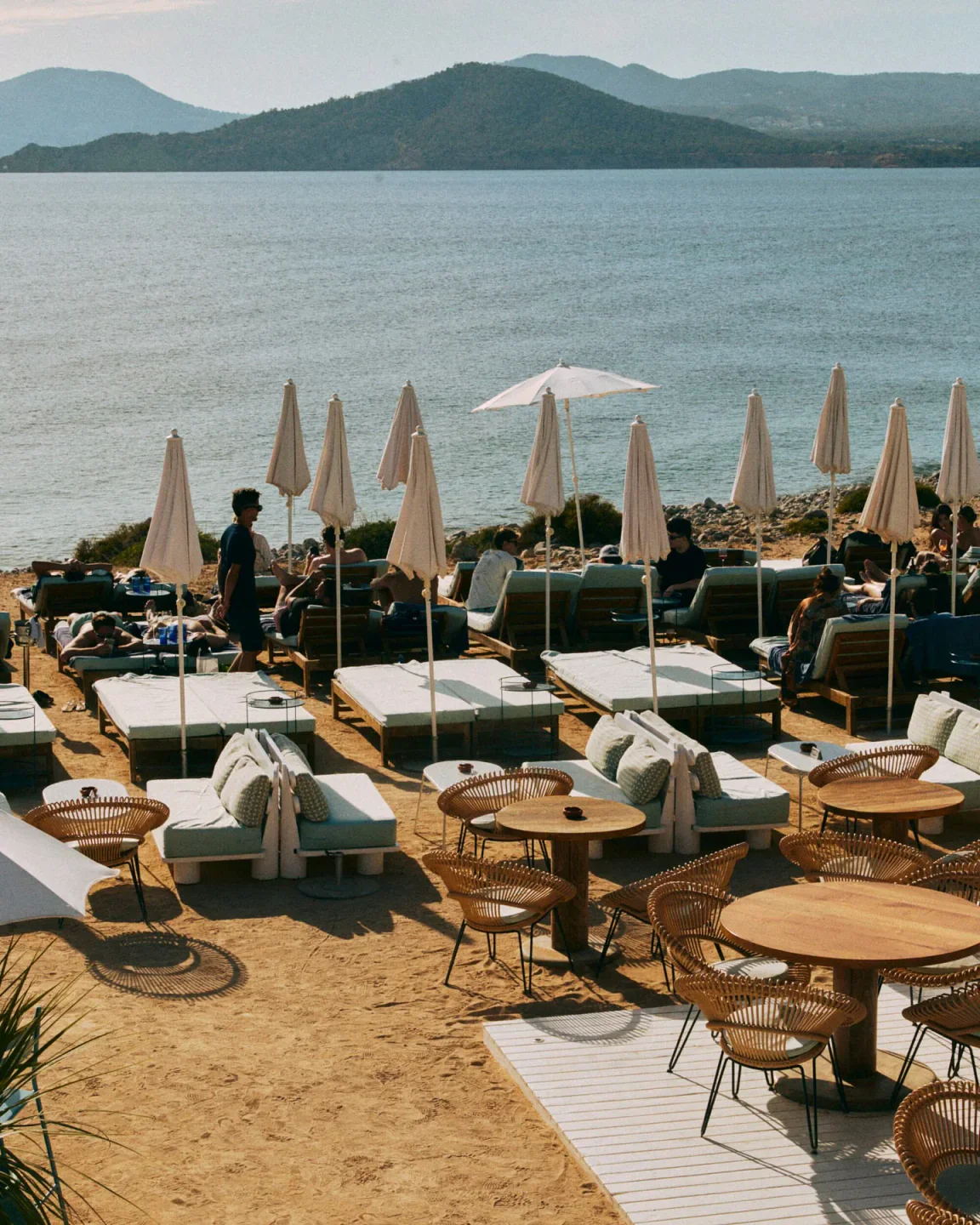 Experimental Beach Ibiza outdoor seating area with lounge beds and umbrellas by the sea.