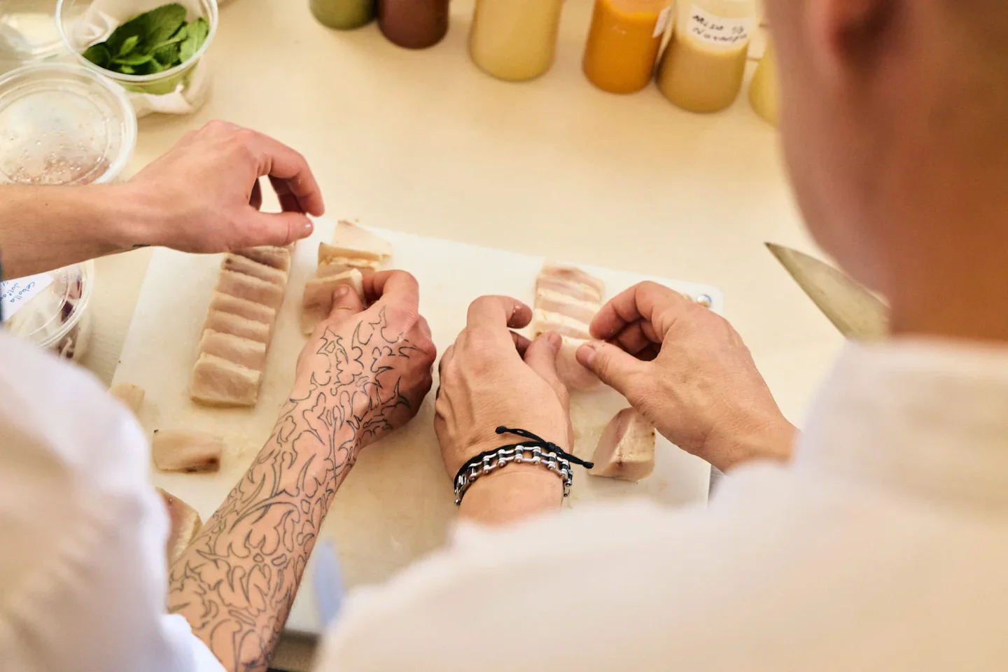 Chefs preparing raw fish slices at Ikisaki restaurant in the city, showcasing culinary skill.