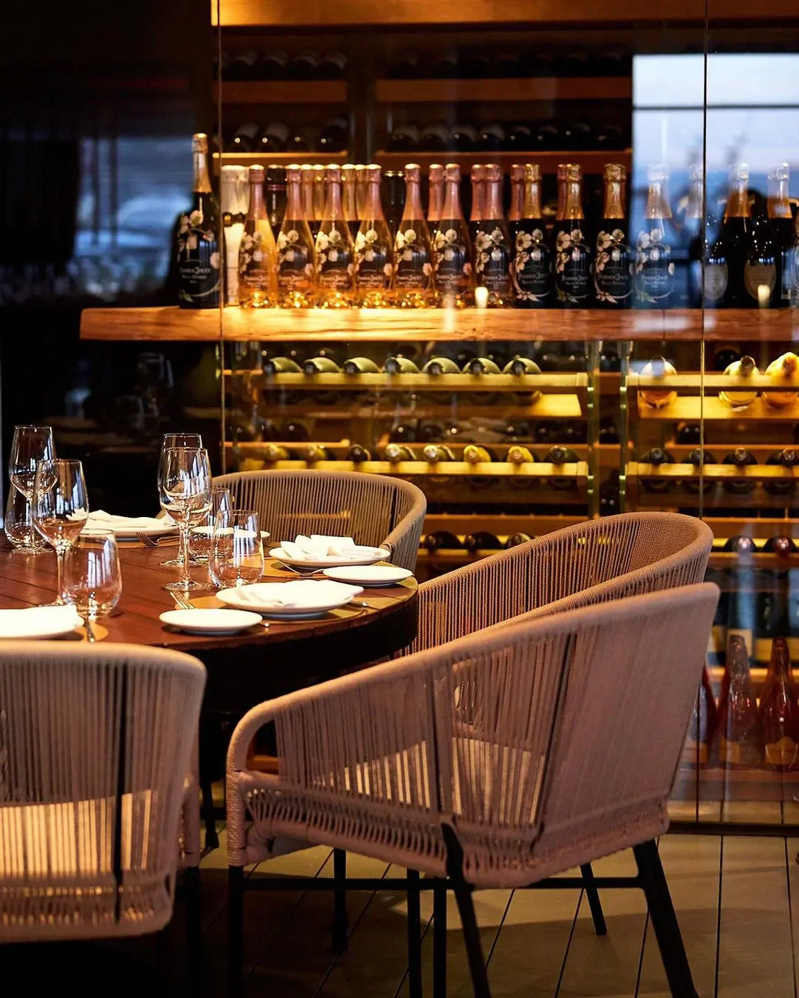 Elegant dining at IT Ibiza, with wine bottles on display in the background.