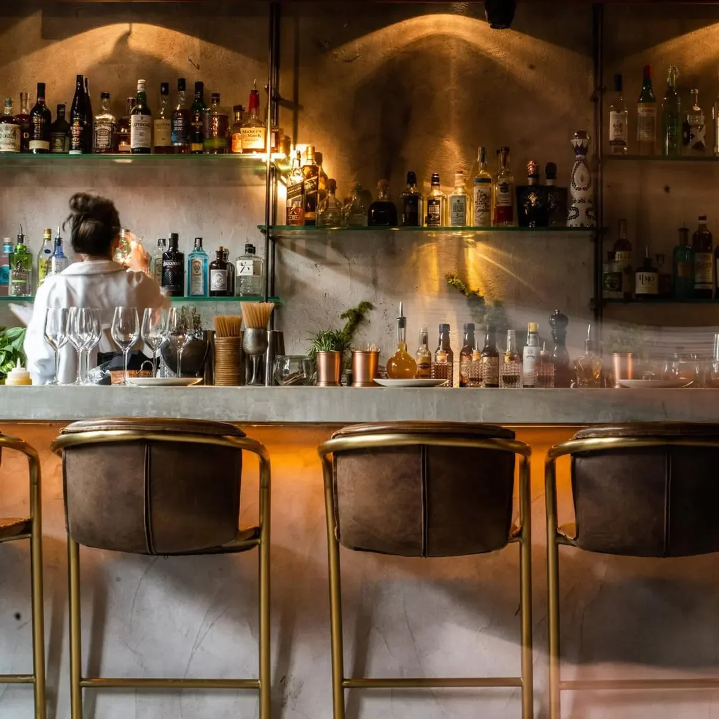 Laylah Ibiza bar interior, with leather stools and a well-stocked bar with many bottles.