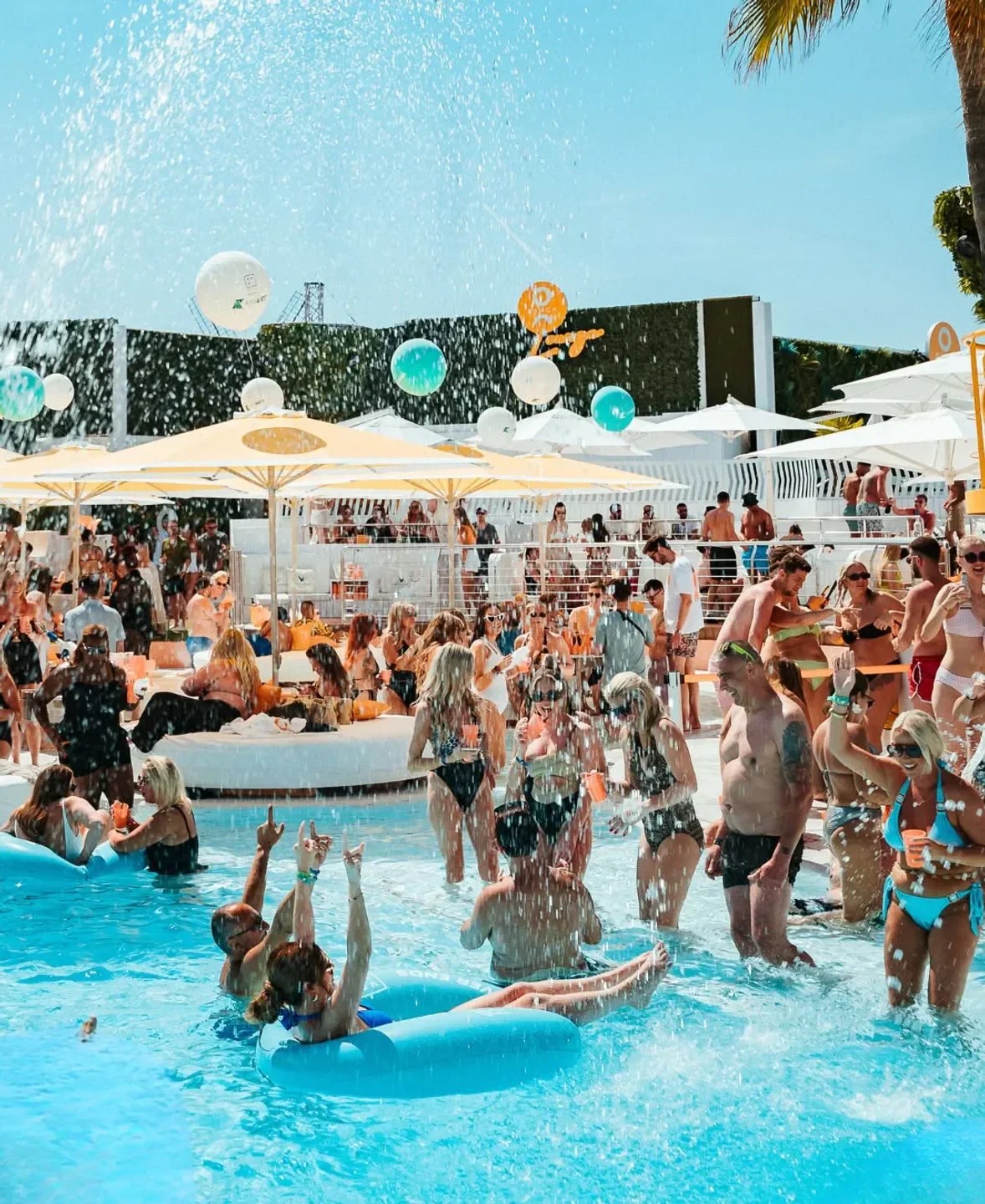 Pool party at O Beach Ibiza, people enjoying the sun and water with balloons.