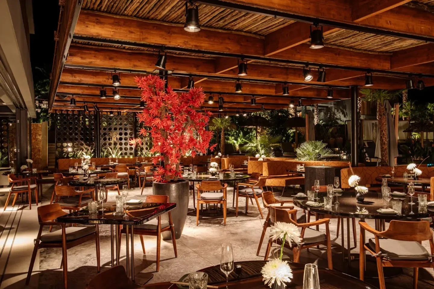 OKU Ibiza restaurant interior featuring tables, chairs, and a striking red tree centerpiece.