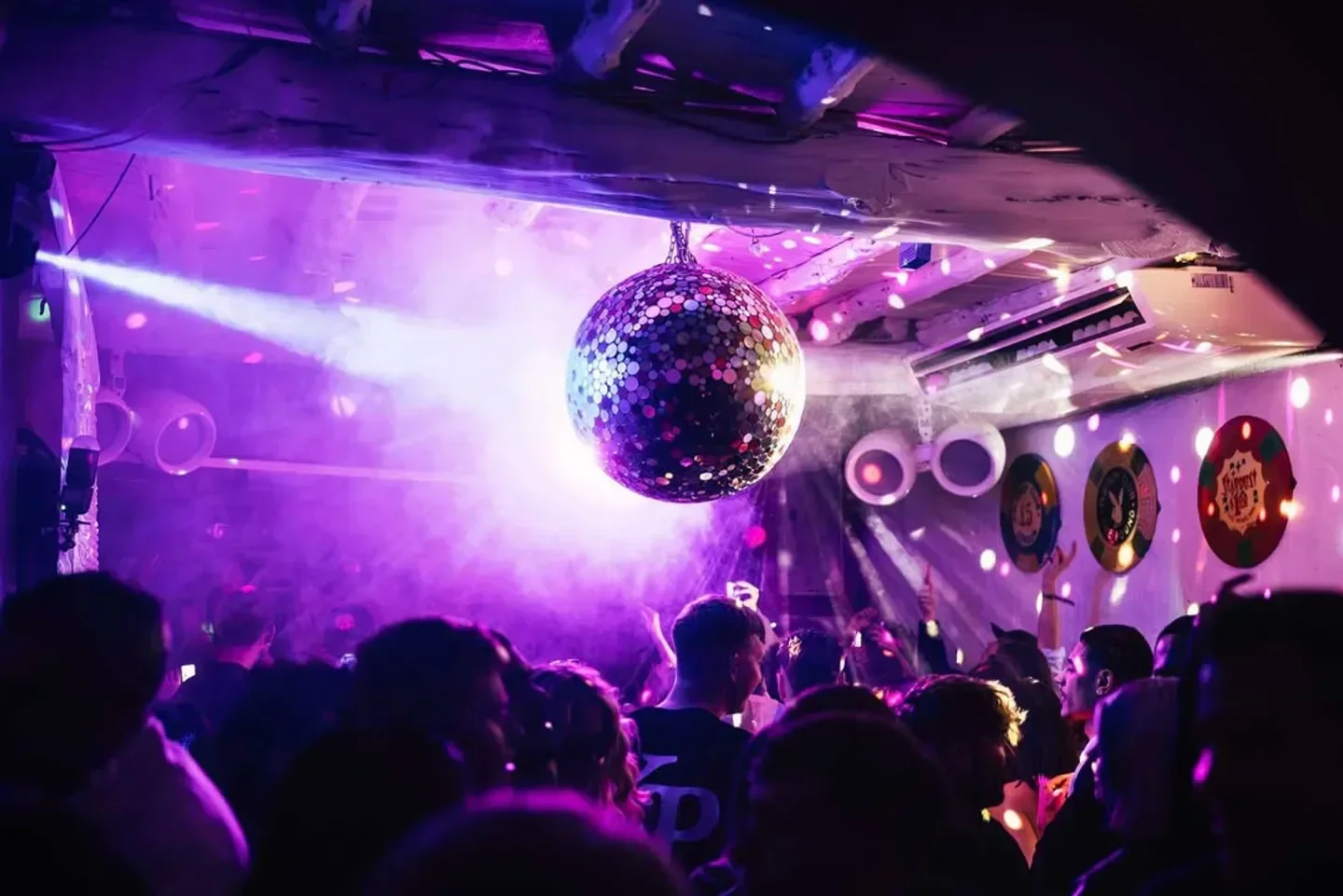 Disco ball and crowd at Pikes nightclub in Ibiza, illuminated by purple lights