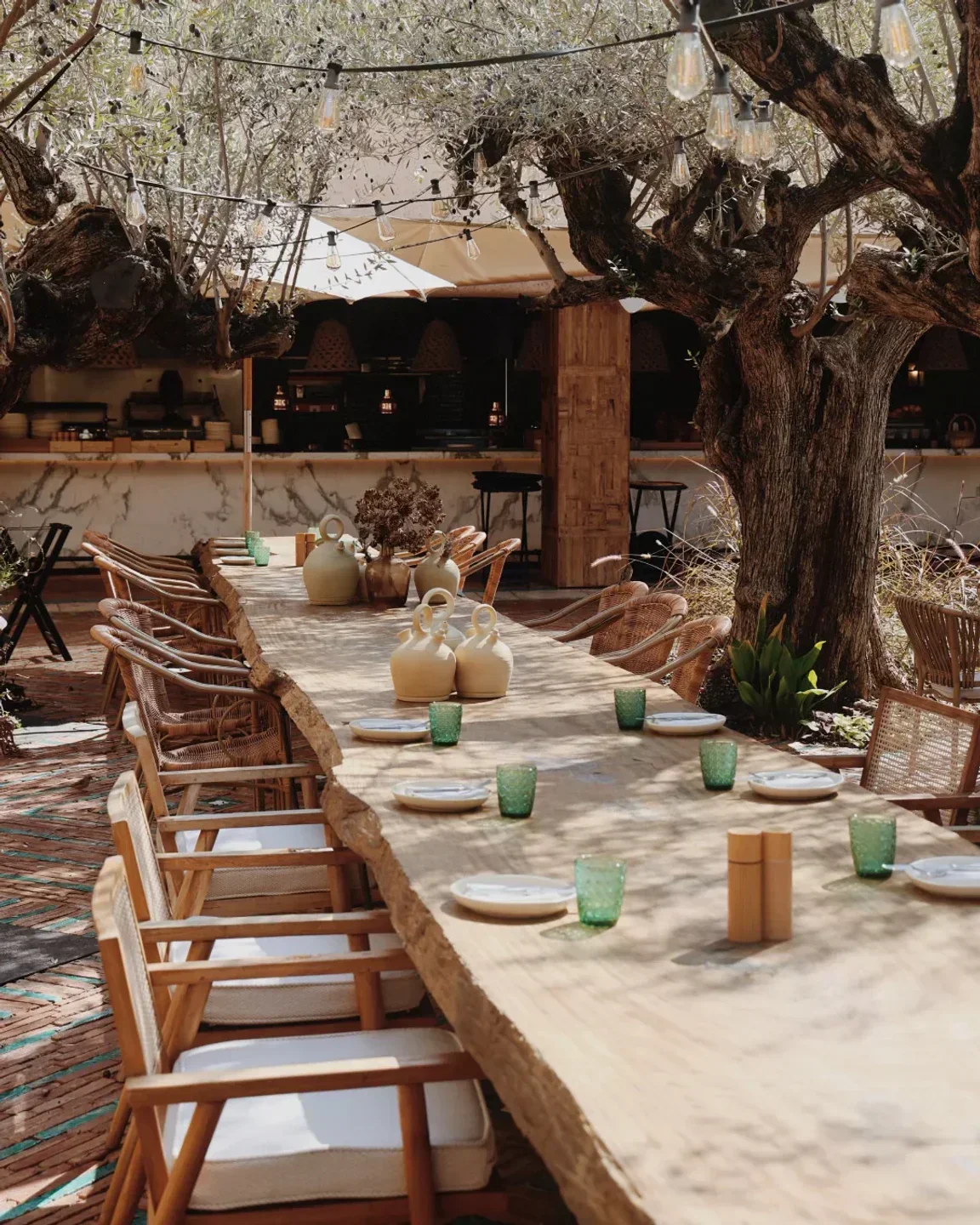 Elegant dining at Six Senses Ibiza, featuring a long wooden table under olive trees.