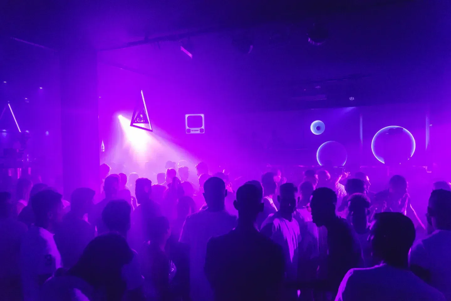 Energetic dance floor at Swag nightclub in Ibiza, illuminated by vibrant purple lights.