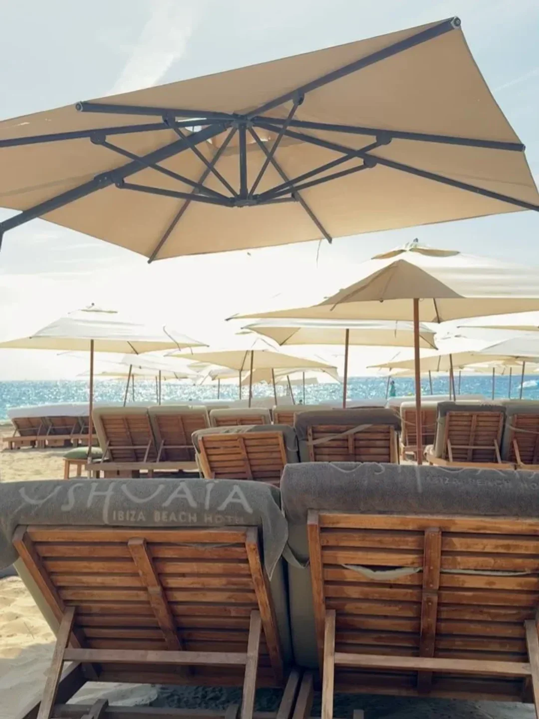 The Beach, Unexpected Ibiza restaurant exterior featuring rows of empty sun loungers on a sandy beach.