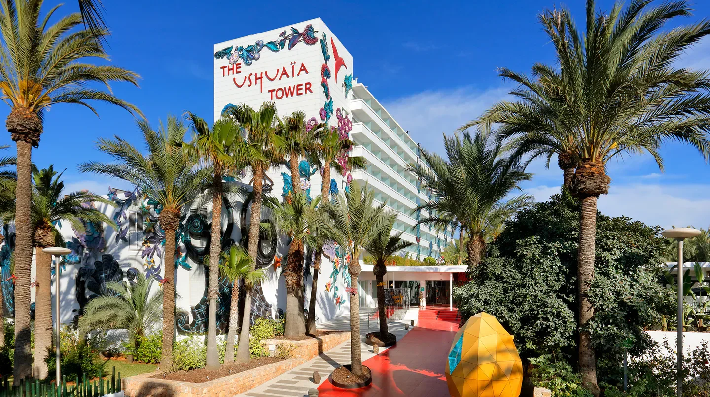 Ushuaïa Ibiza Beach Hotel exterior with palm trees under the Ibiza blue sky.