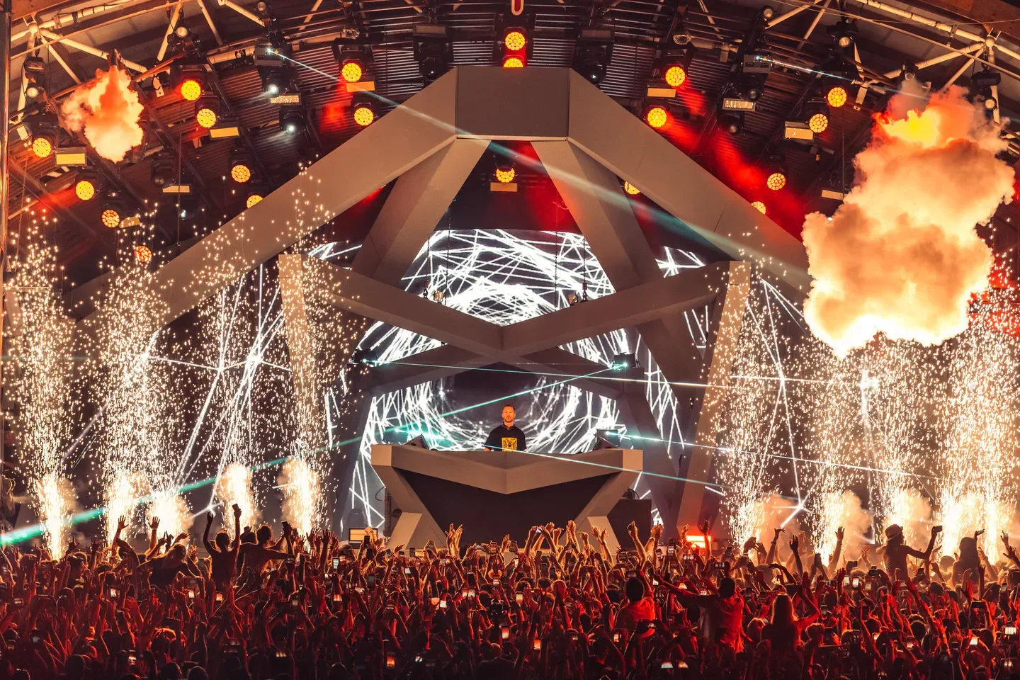 Energetic crowd at Ushuaïa Ibiza with pyrotechnics and DJ performing on stage